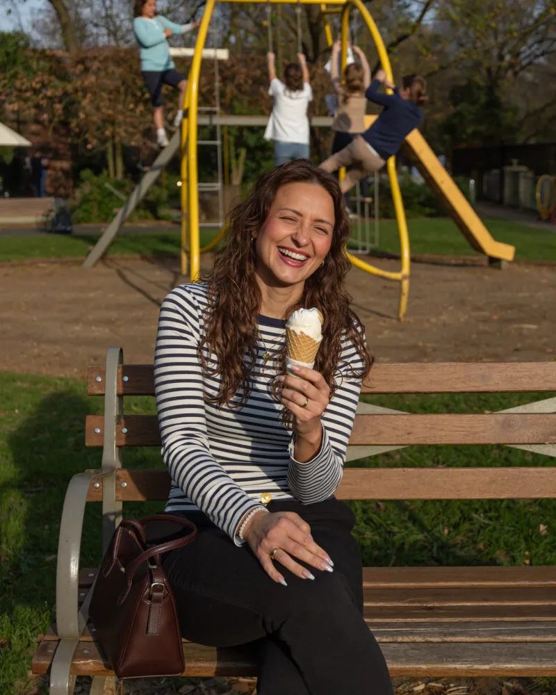 Ina sitzt mit einem Eis am Spielplatz
